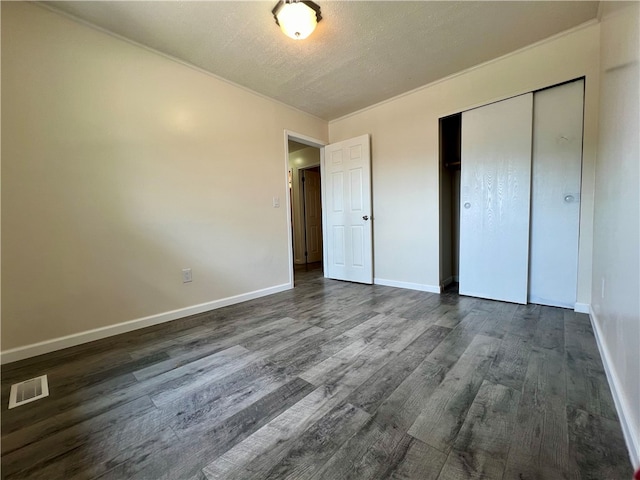 unfurnished bedroom featuring dark wood-type flooring, a closet, and a textured ceiling