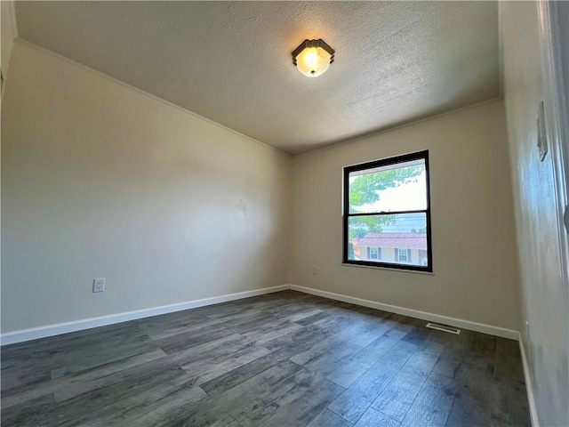 unfurnished room featuring dark wood-type flooring and a textured ceiling