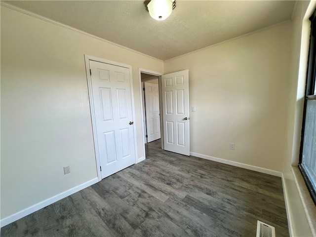 unfurnished bedroom with dark hardwood / wood-style floors, a closet, and a textured ceiling