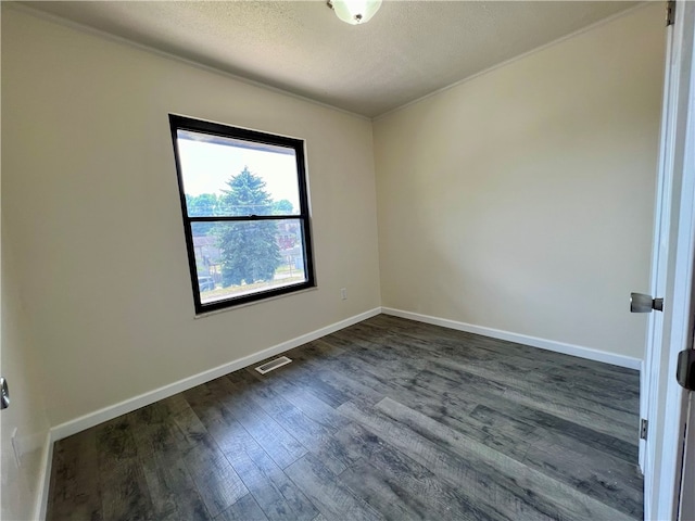 unfurnished room featuring dark wood-type flooring and a textured ceiling