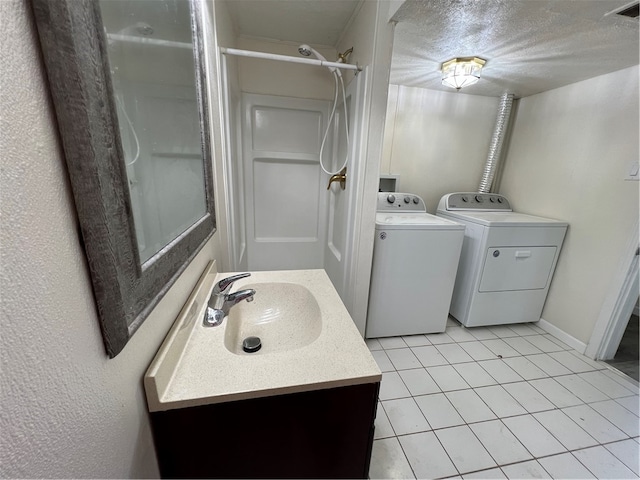 bathroom featuring tile patterned flooring, a shower, washer and clothes dryer, and vanity