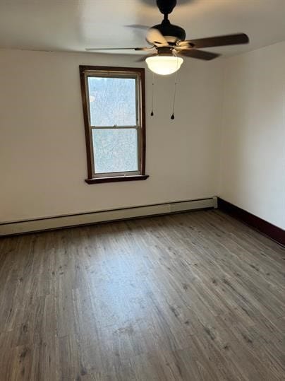 unfurnished room featuring hardwood / wood-style flooring, ceiling fan, and a baseboard heating unit