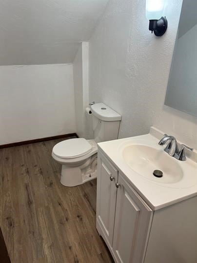 bathroom featuring hardwood / wood-style floors, vanity, vaulted ceiling, and toilet