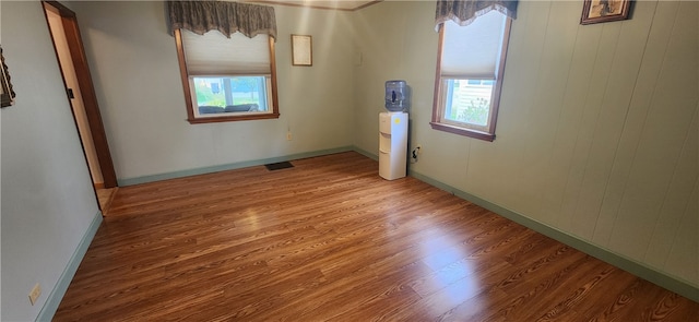 unfurnished room featuring wood walls, hardwood / wood-style flooring, and a healthy amount of sunlight