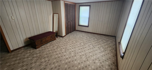 carpeted bedroom featuring wooden walls and a closet