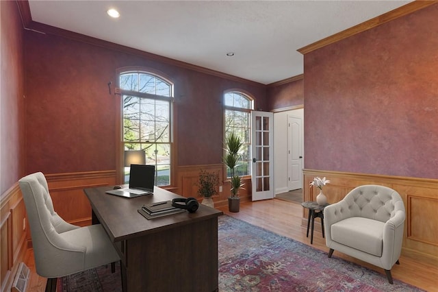 office with light hardwood / wood-style floors, ornamental molding, and french doors