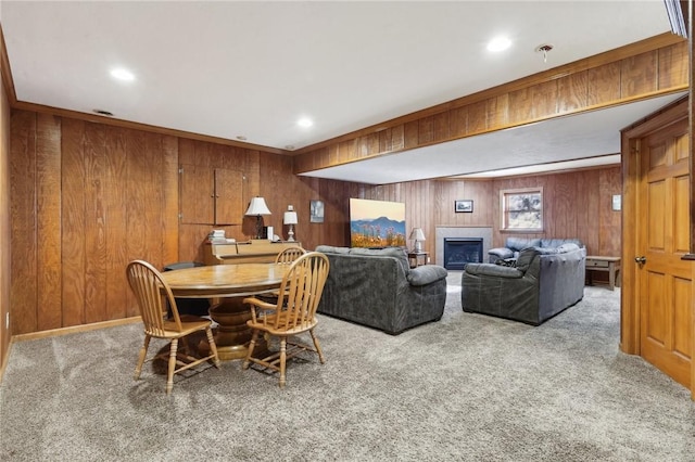 carpeted dining space featuring a tile fireplace and wood walls