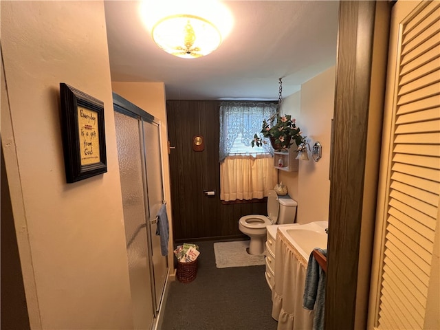 bathroom featuring walk in shower, wooden walls, vanity, and toilet