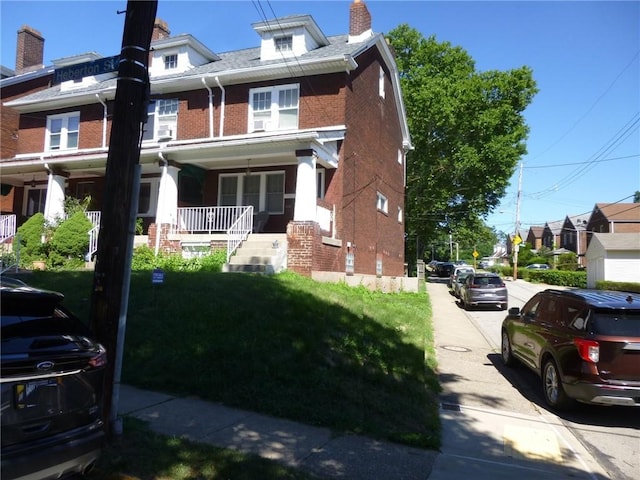 view of front of home with covered porch, brick siding, and a chimney