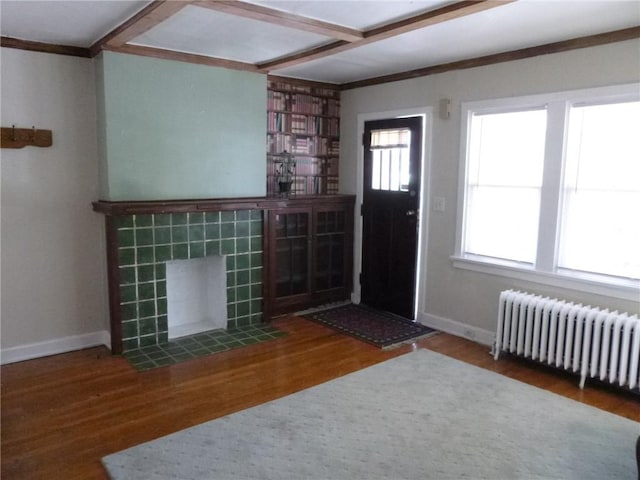 entrance foyer with radiator, baseboards, wood finished floors, and a tile fireplace