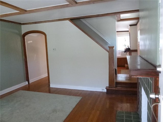 interior space with arched walkways, wood finished floors, baseboards, radiator heating unit, and crown molding