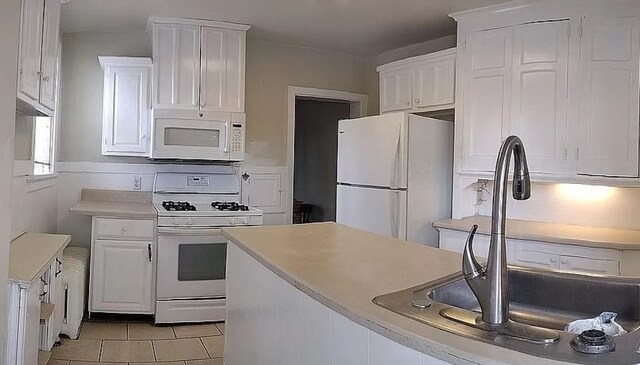 kitchen featuring white cabinetry, sink, white appliances, and light tile patterned floors