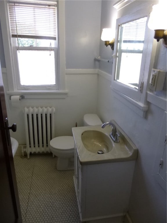 bathroom with tile patterned flooring, radiator, toilet, and vanity