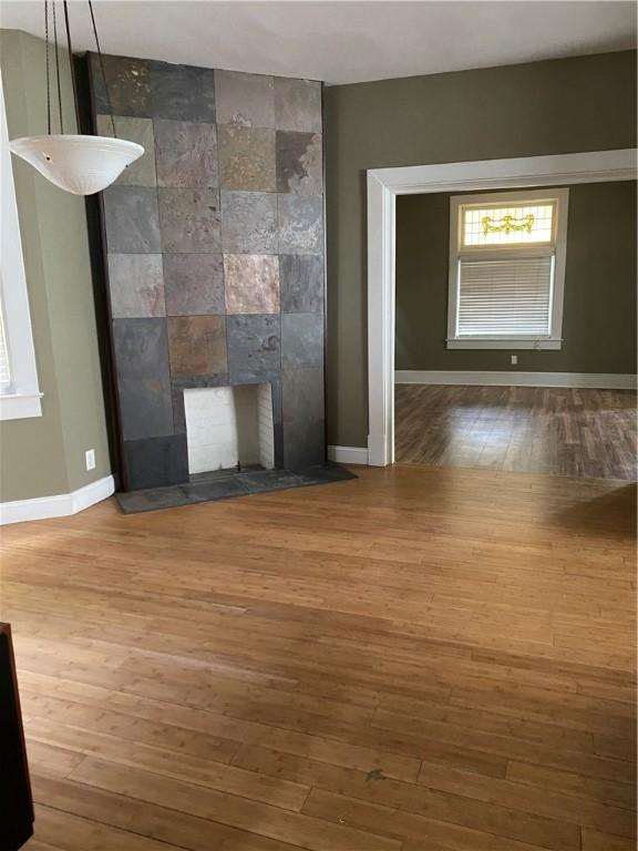 unfurnished living room with a fireplace, hardwood / wood-style flooring, and tile walls