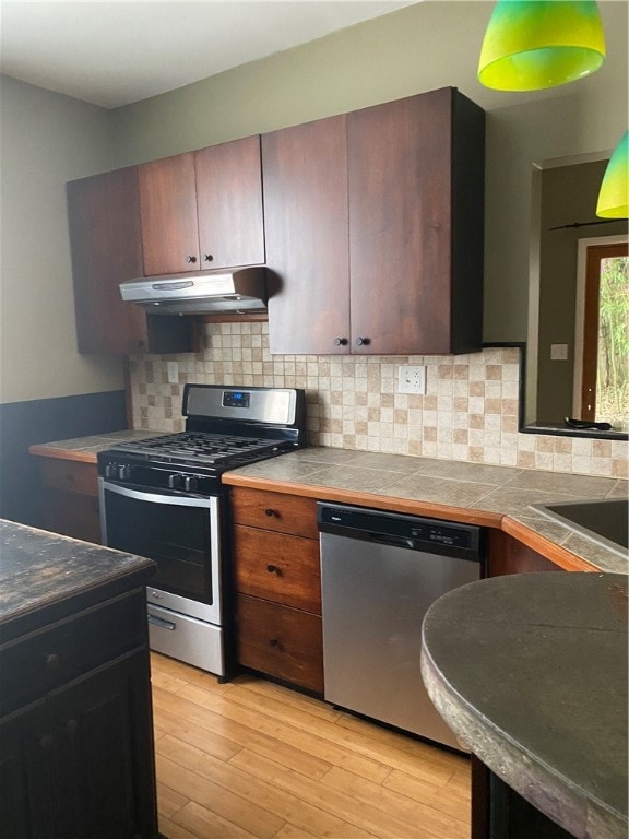 kitchen with tasteful backsplash, light wood-type flooring, stainless steel appliances, tile countertops, and sink