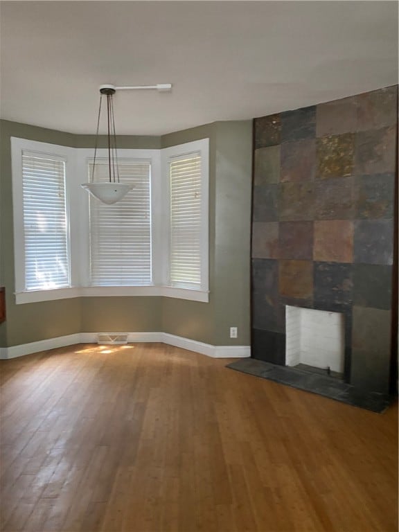 unfurnished living room with a tile fireplace and hardwood / wood-style flooring