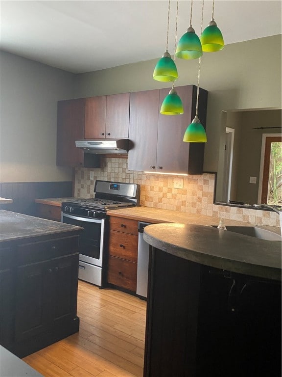 kitchen featuring light hardwood / wood-style flooring, sink, hanging light fixtures, gas stove, and backsplash