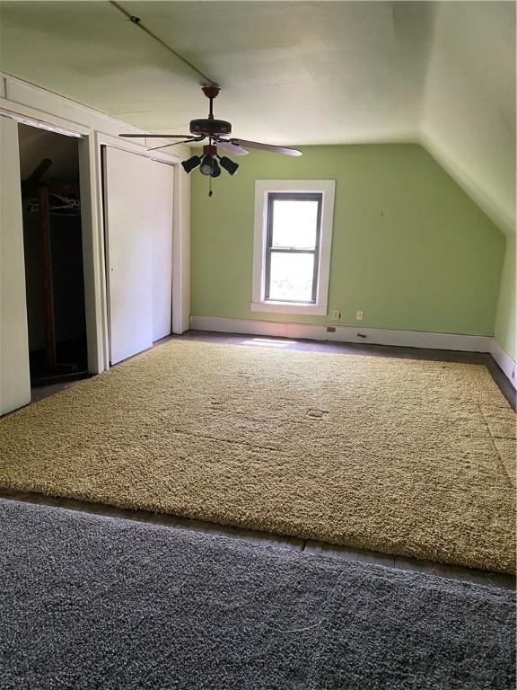 additional living space with vaulted ceiling, carpet floors, and ceiling fan