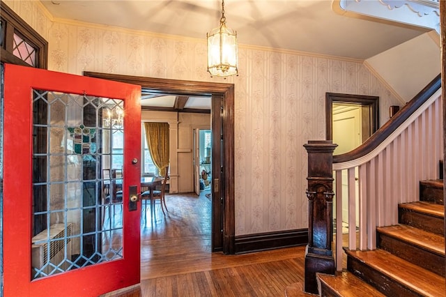 foyer featuring lofted ceiling, french doors, hardwood / wood-style flooring, ornamental molding, and a chandelier