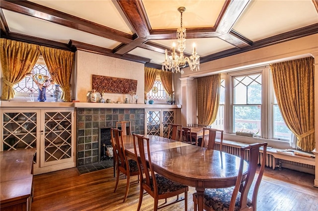 dining area with hardwood / wood-style floors, coffered ceiling, a fireplace, and an inviting chandelier