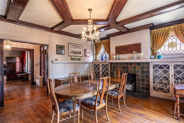 dining space with coffered ceiling, wood-type flooring, a fireplace, and a chandelier