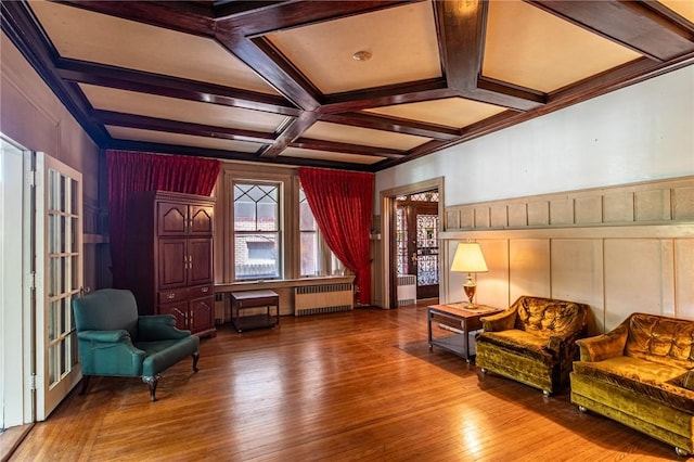 sitting room featuring radiator heating unit, beam ceiling, coffered ceiling, and hardwood / wood-style floors