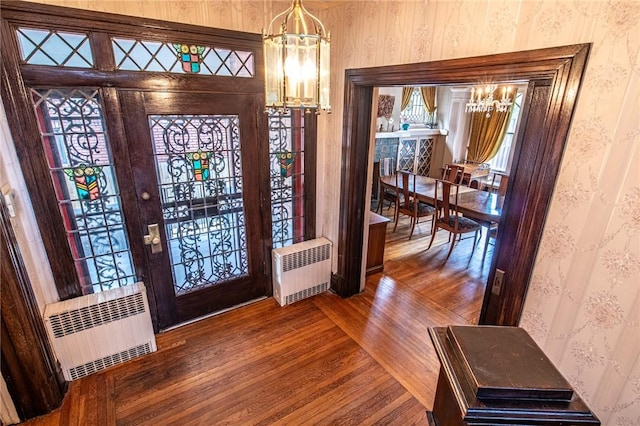 entryway with wood-type flooring, an inviting chandelier, and radiator