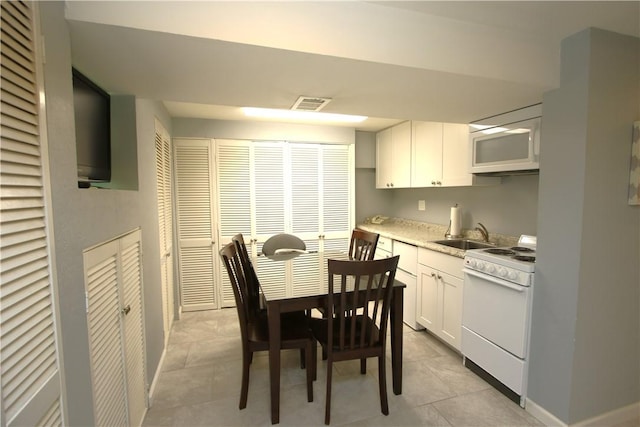 kitchen featuring sink, white appliances, light tile patterned floors, and white cabinets