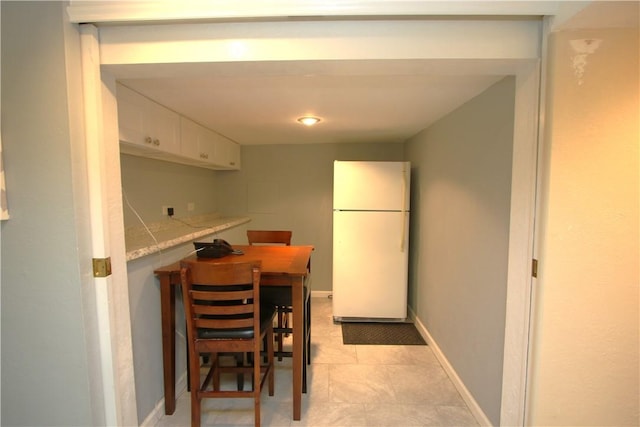 kitchen with white cabinets, white fridge, and light stone counters