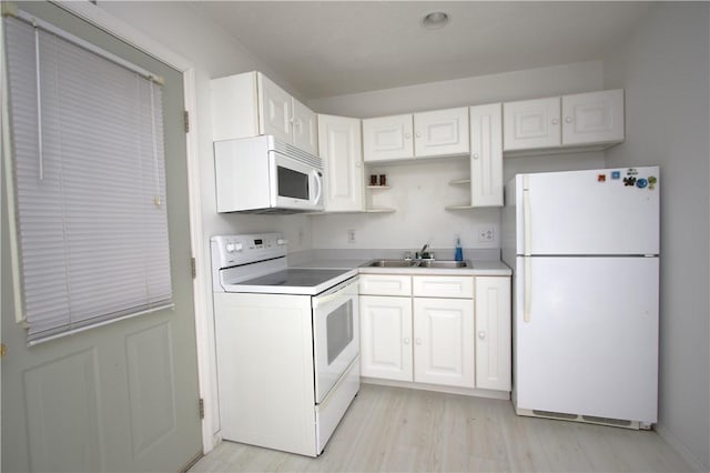 kitchen with white appliances, white cabinetry, light wood-type flooring, and sink