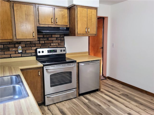 kitchen with stainless steel appliances, sink, light hardwood / wood-style flooring, and decorative backsplash