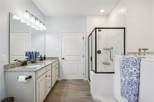 bathroom featuring dual vanity, a shower with shower door, and hardwood / wood-style floors