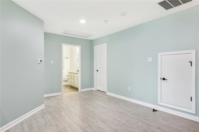 unfurnished bedroom featuring ensuite bath and light hardwood / wood-style floors