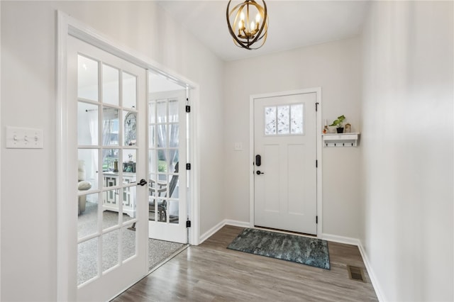 entrance foyer with hardwood / wood-style flooring, a notable chandelier, and french doors