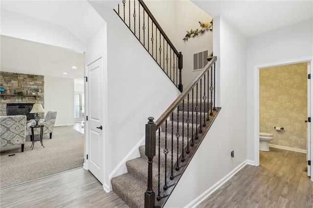 stairway featuring carpet floors and a stone fireplace