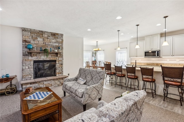 living room featuring a stone fireplace, light hardwood / wood-style floors, and a textured ceiling