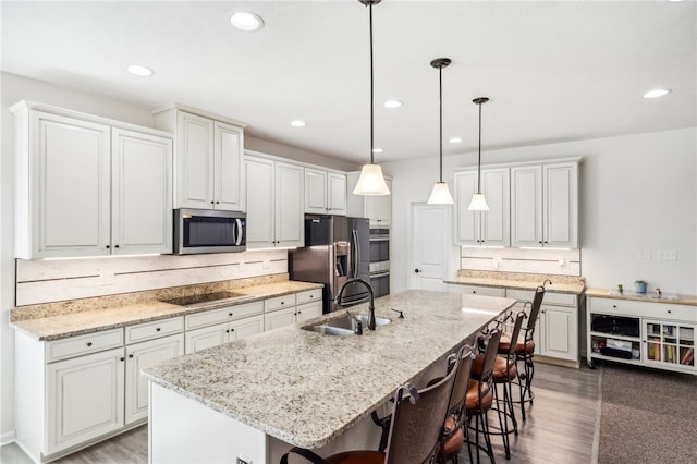 kitchen featuring a center island with sink, a kitchen bar, hardwood / wood-style floors, appliances with stainless steel finishes, and sink