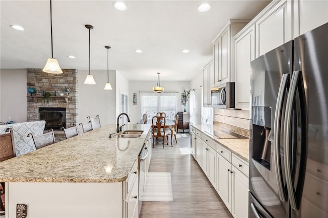 kitchen featuring a fireplace, tasteful backsplash, hardwood / wood-style floors, sink, and appliances with stainless steel finishes