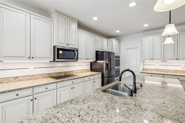 kitchen featuring white cabinetry, stainless steel appliances, hanging light fixtures, sink, and light stone counters