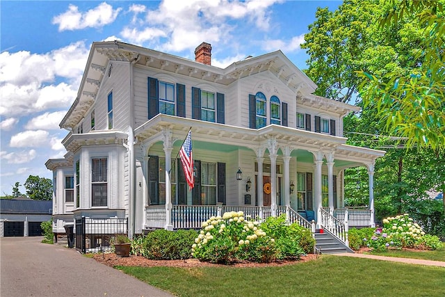 italianate-style house with a front lawn, a porch, and a garage