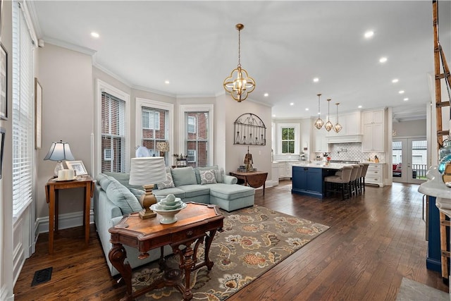 living room featuring dark hardwood / wood-style floors, ornamental molding, and a notable chandelier