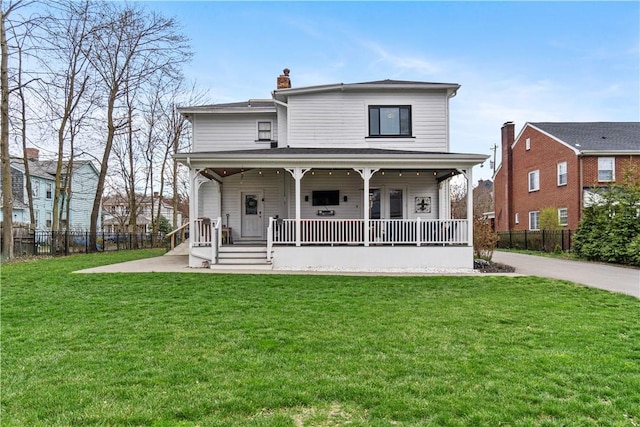 rear view of house featuring covered porch and a lawn