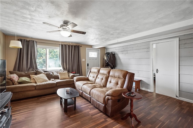 living room with ceiling fan, dark wood-type flooring, and a textured ceiling