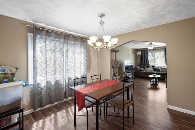 dining room featuring ceiling fan with notable chandelier and dark wood-type flooring