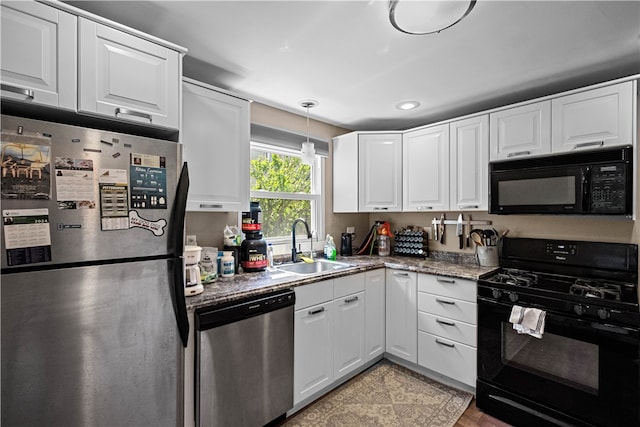 kitchen featuring decorative light fixtures, sink, white cabinetry, black appliances, and light stone counters