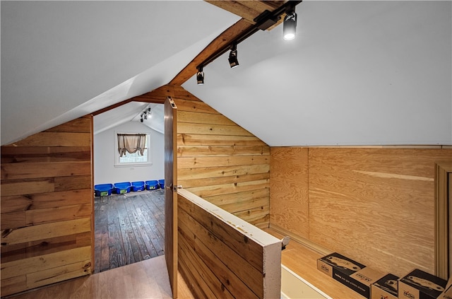 additional living space featuring hardwood / wood-style flooring, wooden walls, and vaulted ceiling with beams