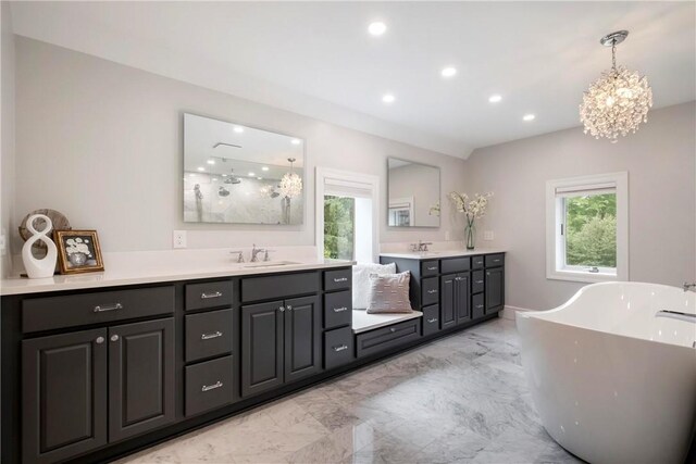 bathroom featuring an inviting chandelier, vanity, tile patterned floors, and a tub to relax in