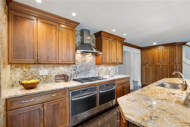 kitchen with wall chimney range hood, stainless steel appliances, dark tile patterned floors, decorative backsplash, and sink