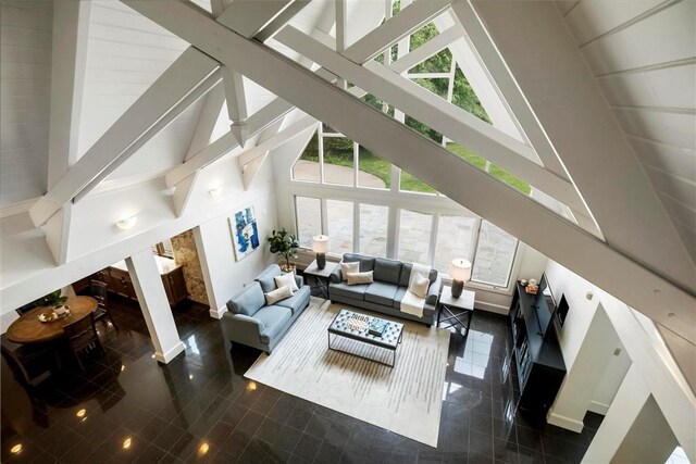 living room featuring beam ceiling, dark tile patterned flooring, and high vaulted ceiling