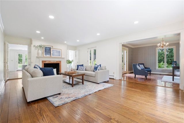 living room with a fireplace, baseboard heating, a wealth of natural light, and hardwood / wood-style flooring